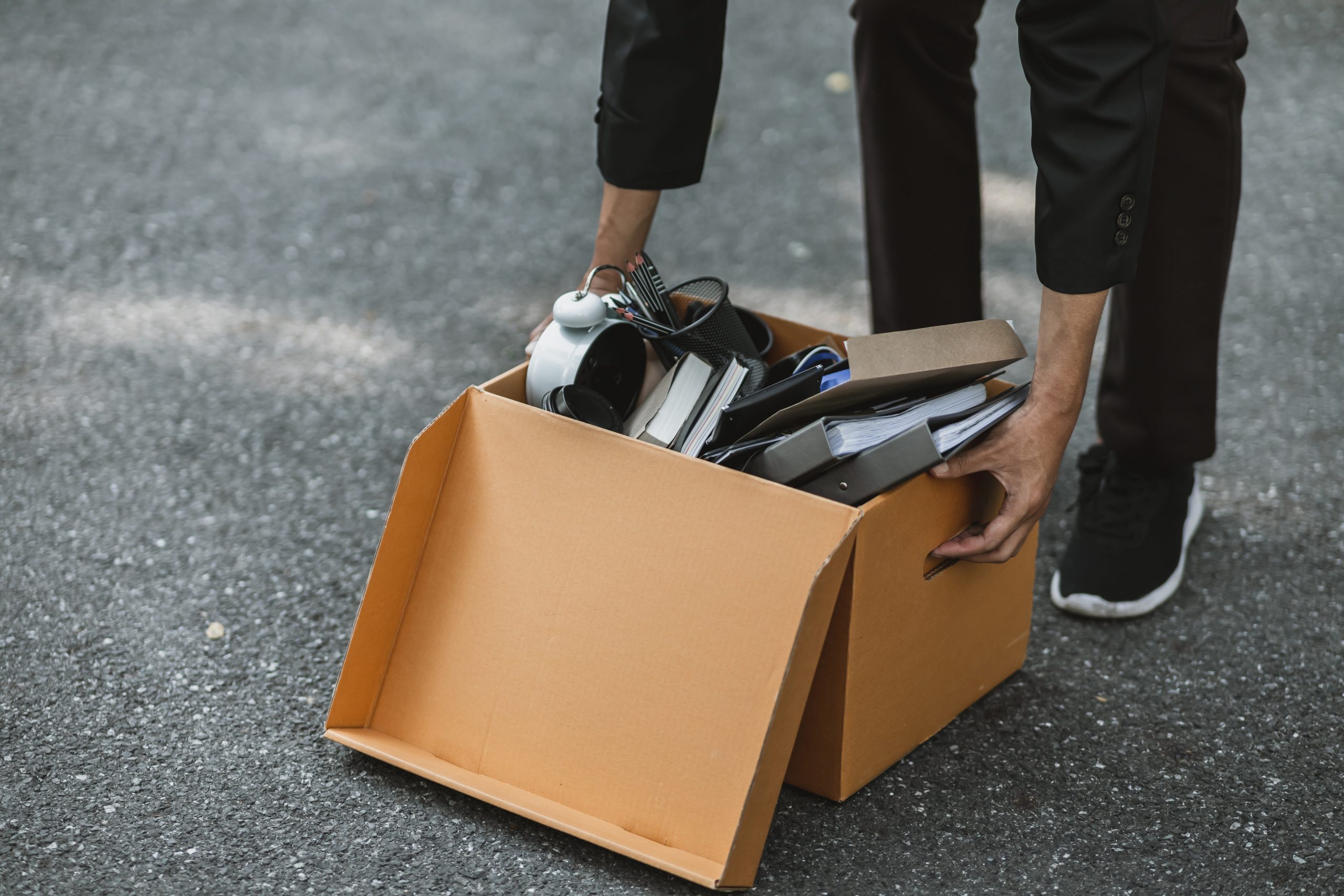 Businessperson carrying boxes in the street. Image: Adobe Stock